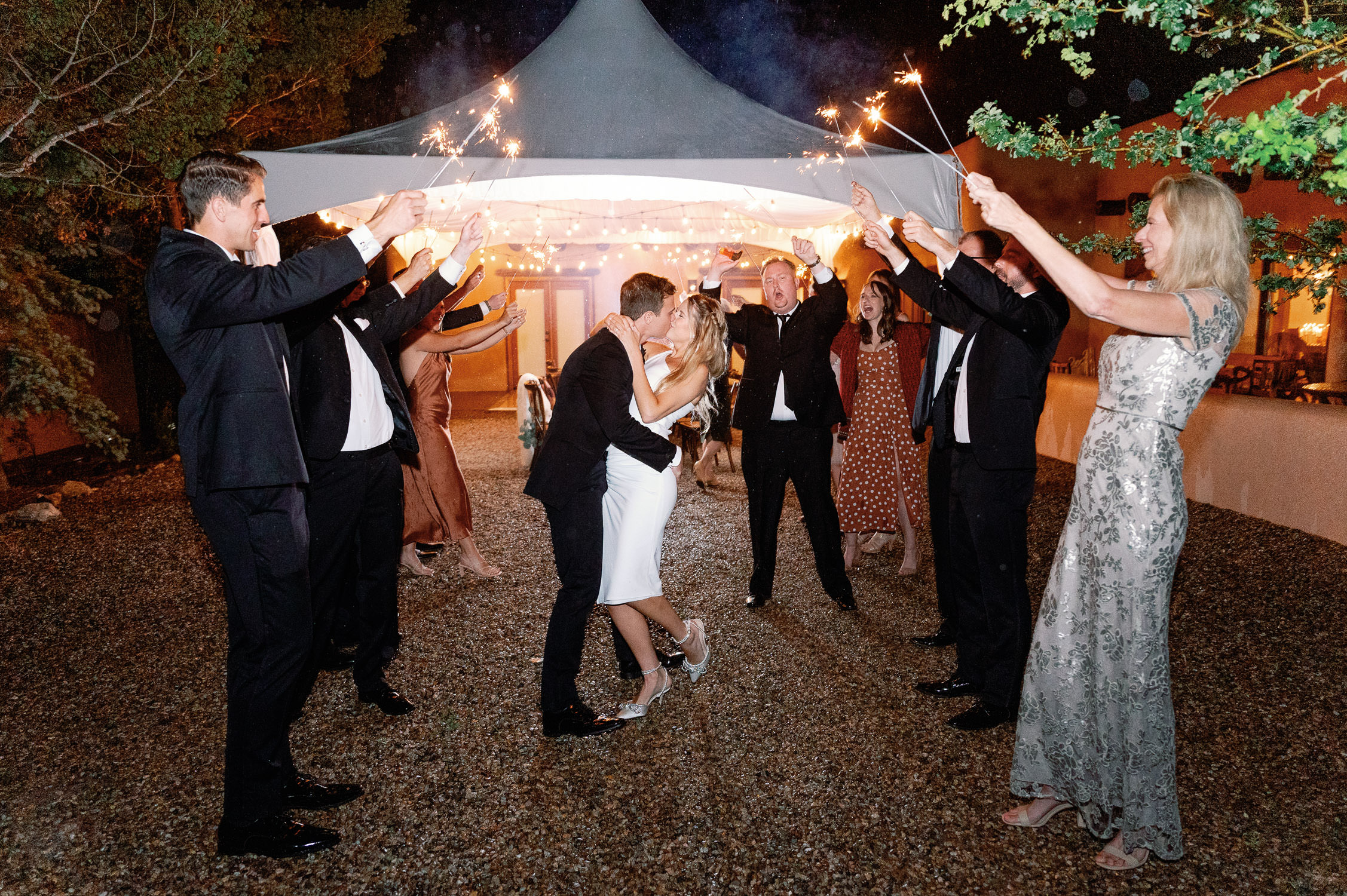 Chic Bride and Groom leave wedding while guests hold sparklers.