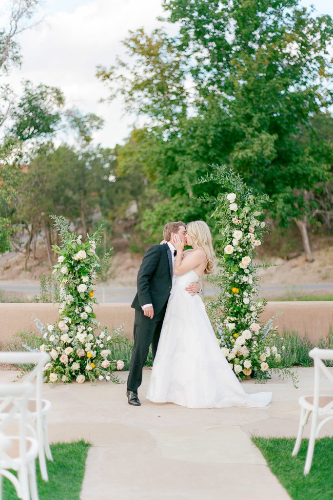 Bride and Groom kiss in front of floral wedding arch