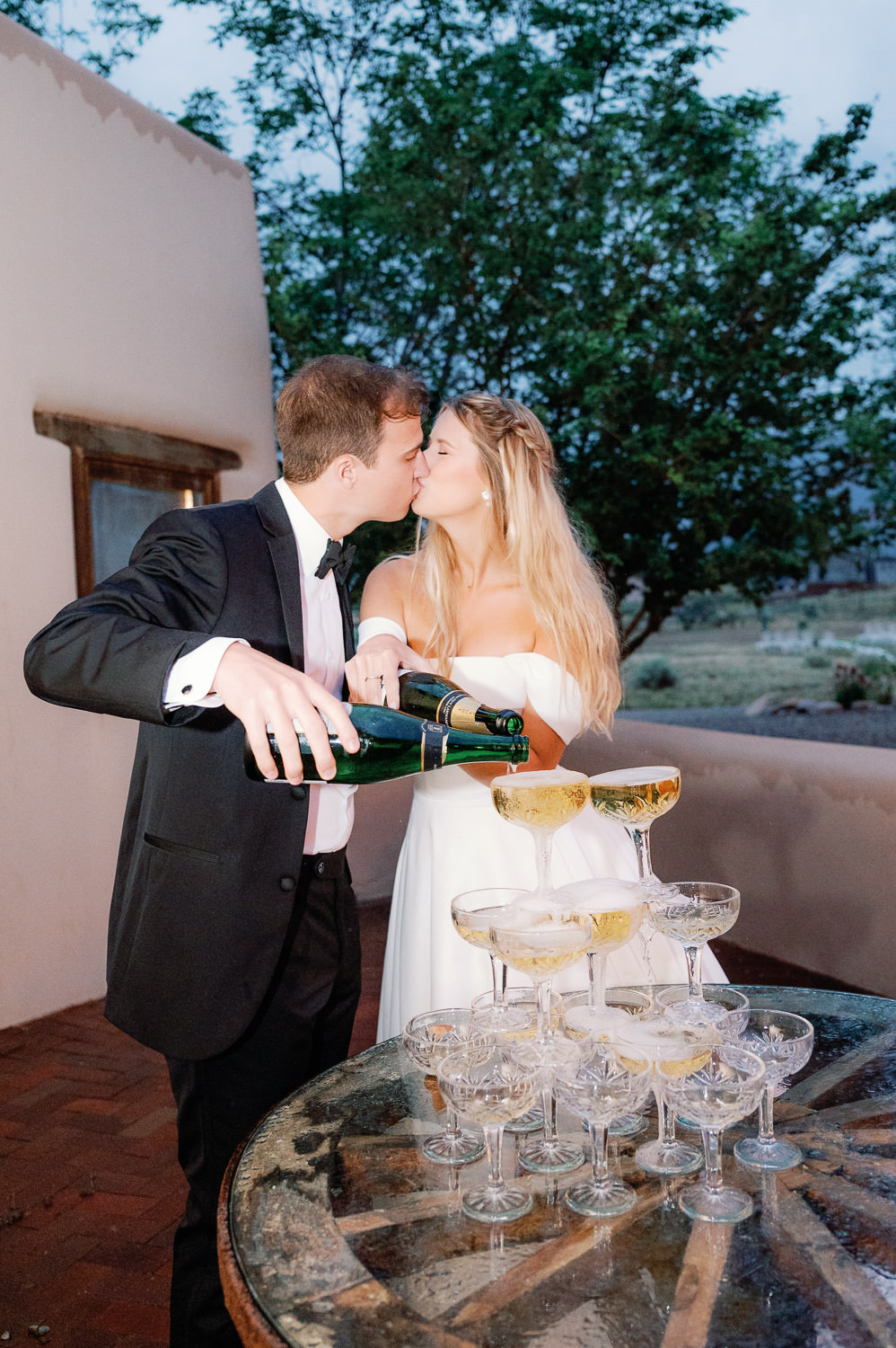 bride and groom kiss as the pour champagne