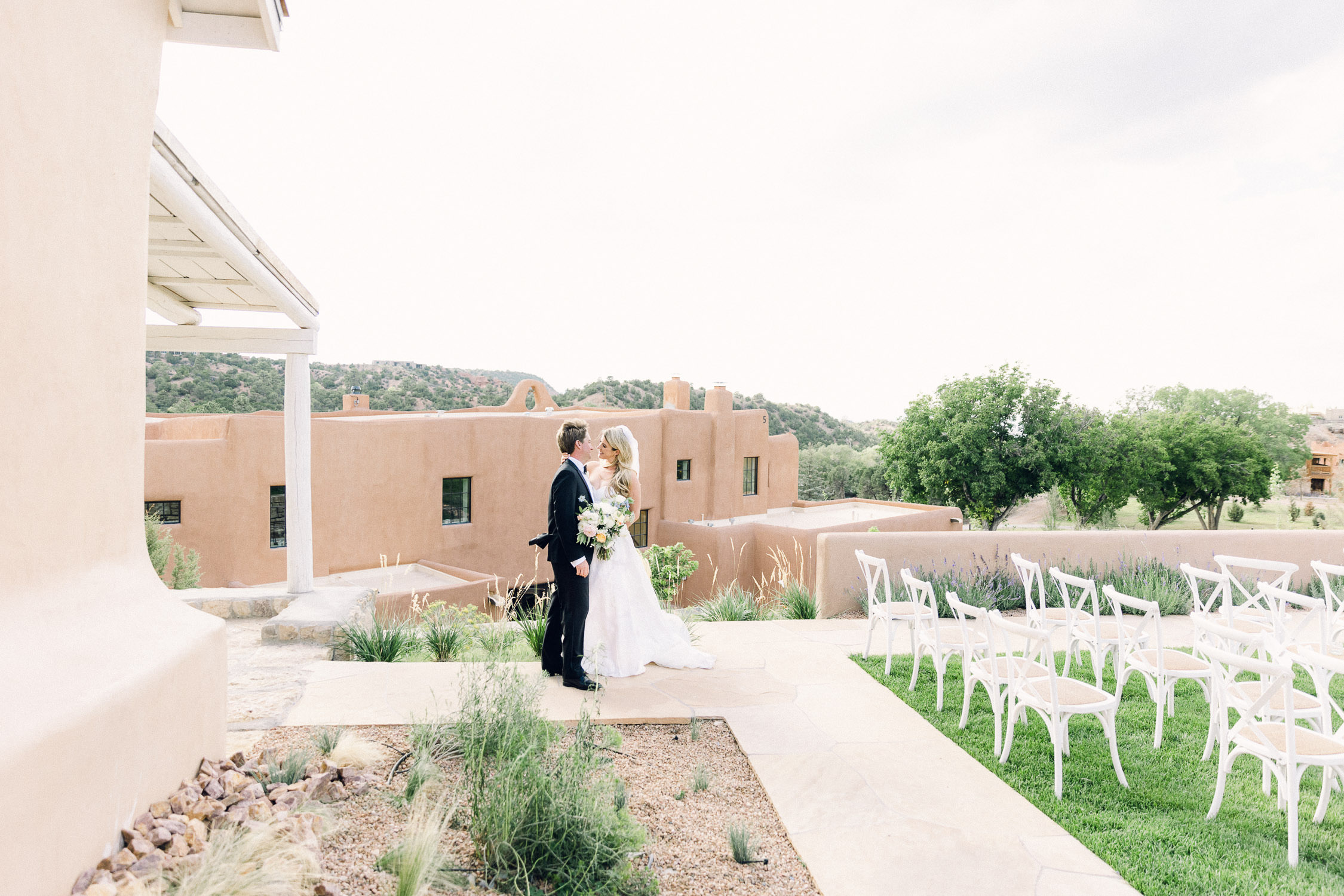 Bride and Groom stand in front of adobe buildings after their wedding ceremony.
