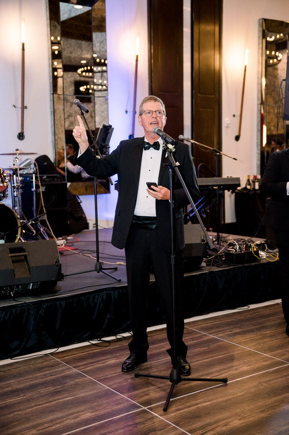 Man in a black tux gives a speech.