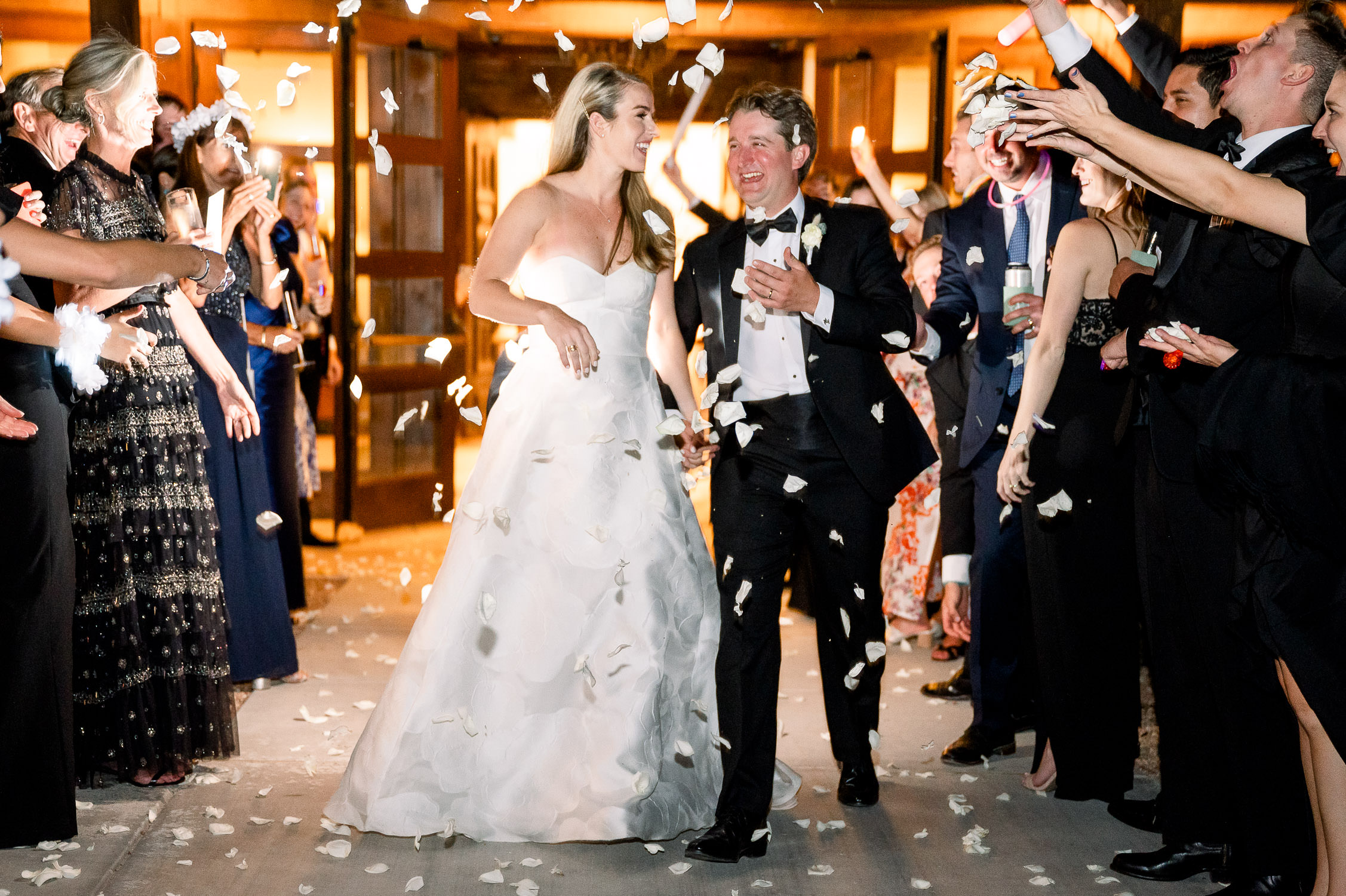 Bride and groom exit bishop's lodge with white rose petals thrown at them.
