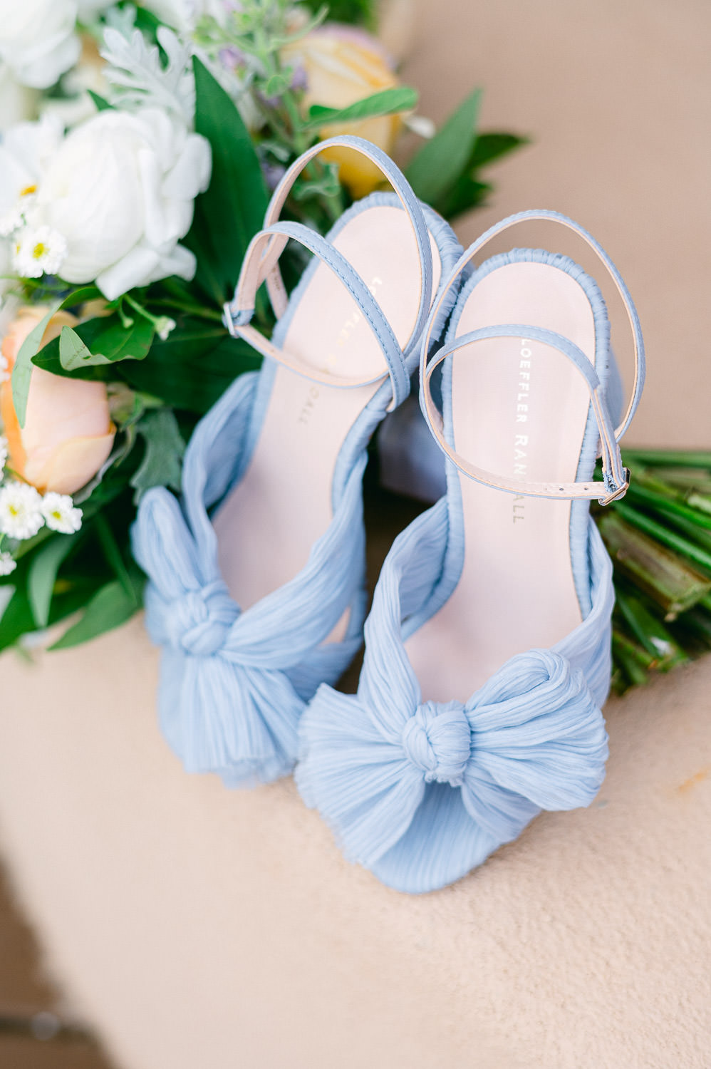Blue Loeffler Randall wedding sandals in front of a bouquet.
