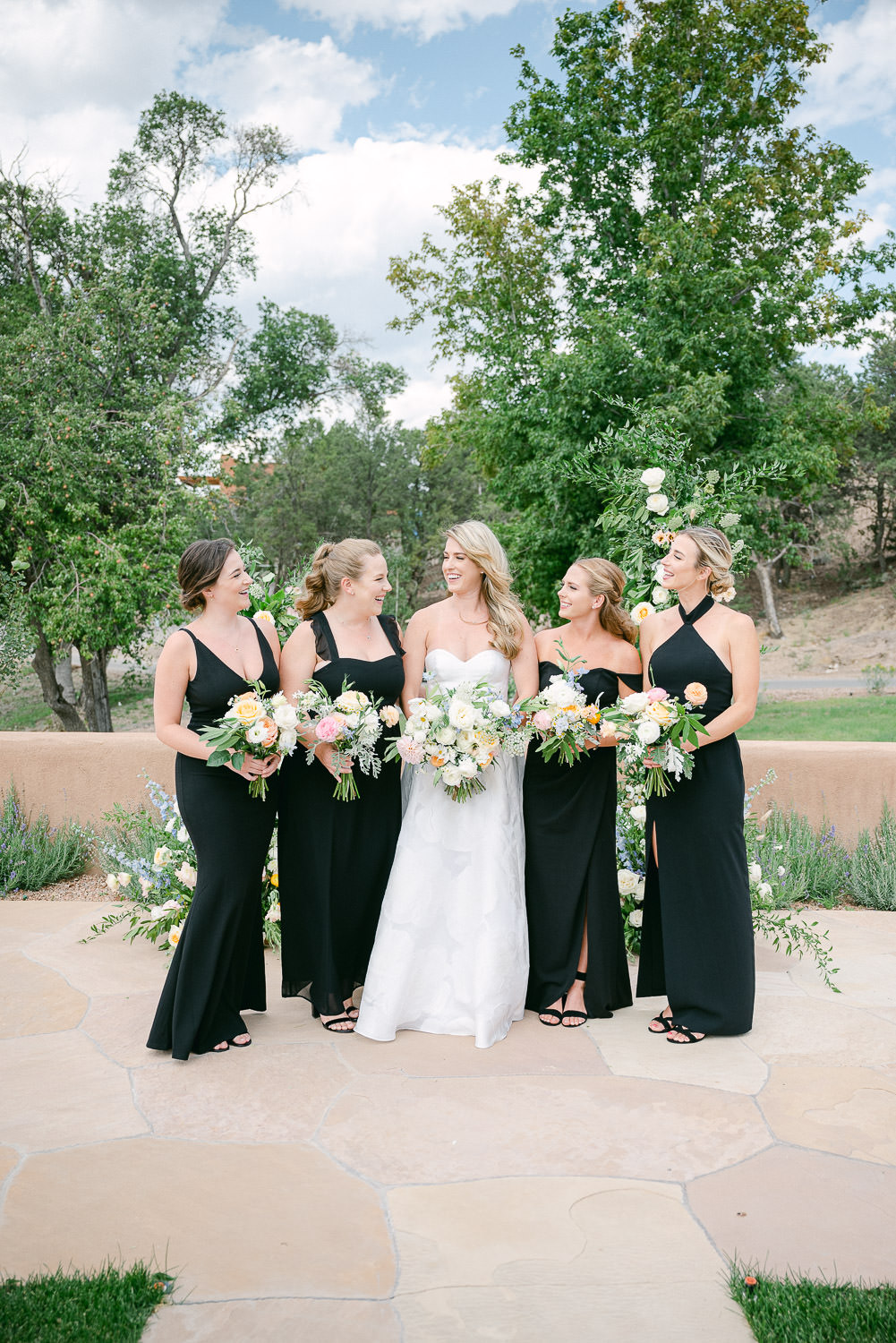 Bride and Bridesmaids in front of a floral wedding arch.