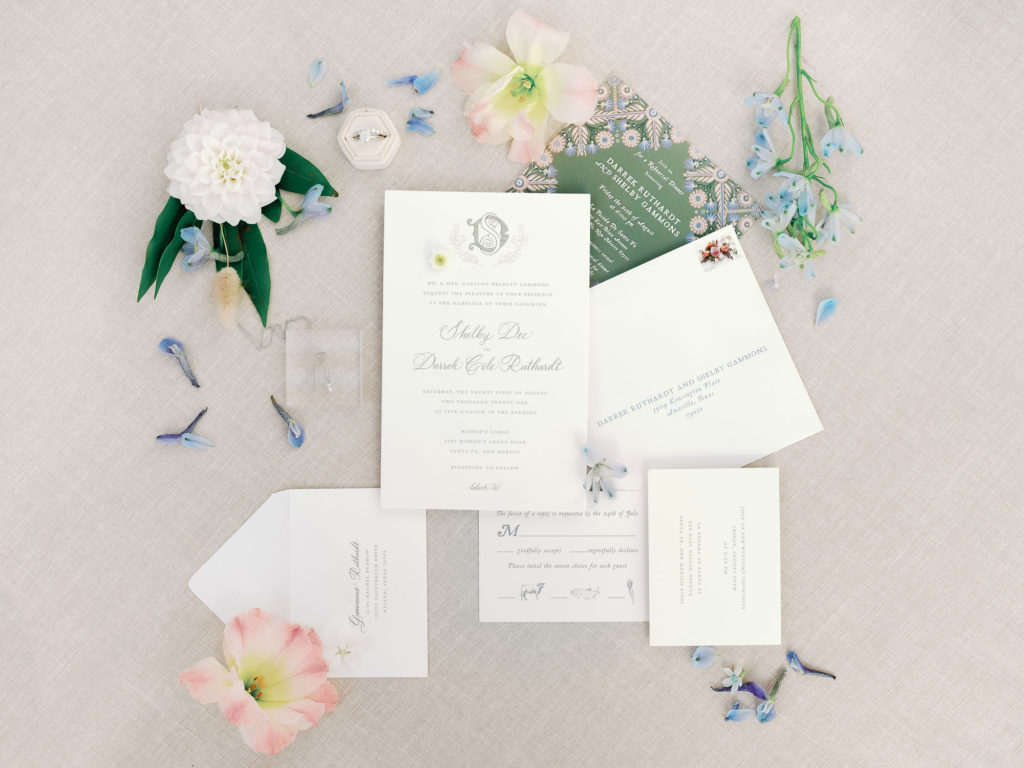 Flay lay image of wedding invite with floral accents.
